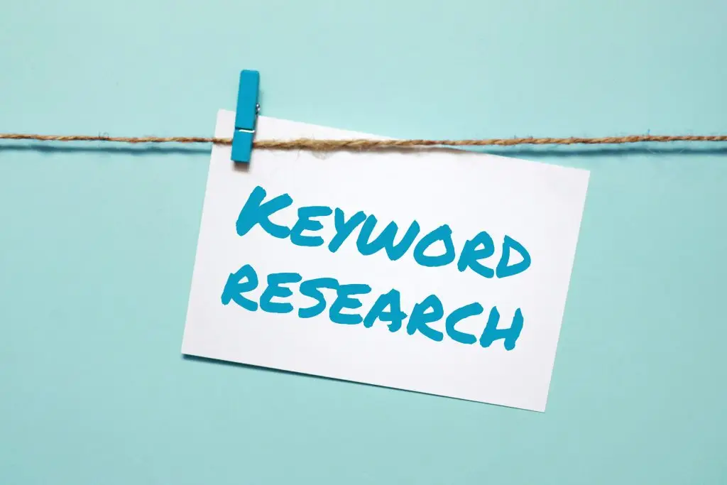 A 2D visual of a piece of paper with the text "keyword research" hung on a clothes line to represent the near me keyword research discussed in the section