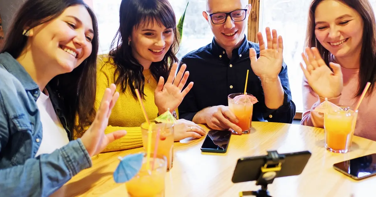 a group of people building a personal brand on social media posing and waving at a phone while they are recording