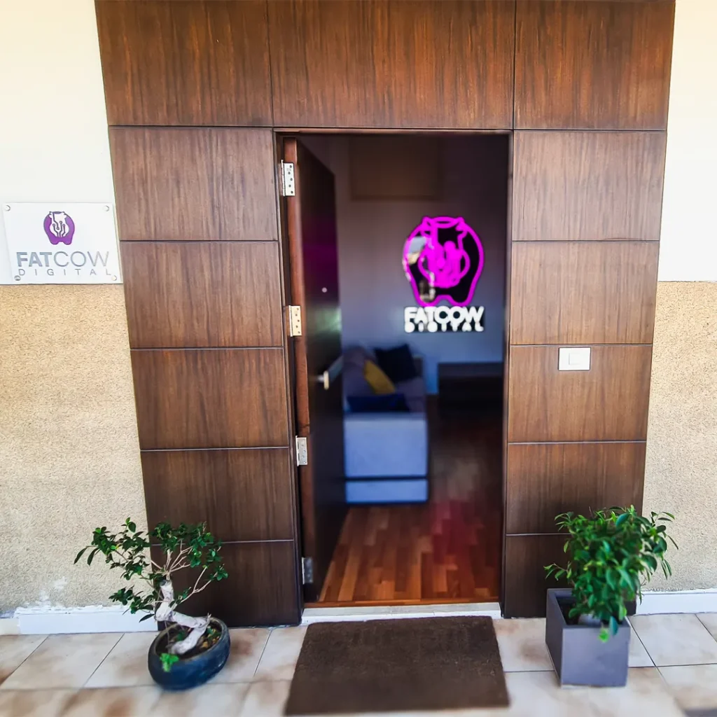 Brown door entrance to a Digital Marketing agency showing the LED logo inside and plants on the sides